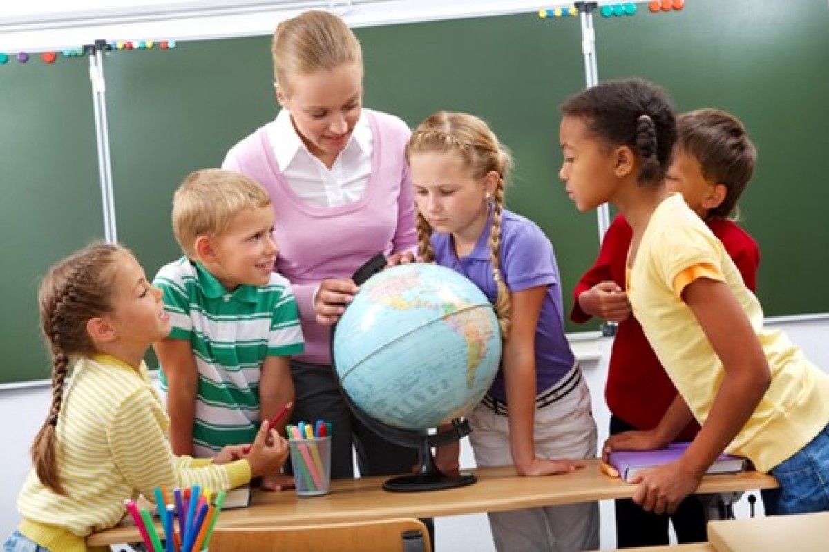 Teacher teaching children on a globe | Best Playschool near me